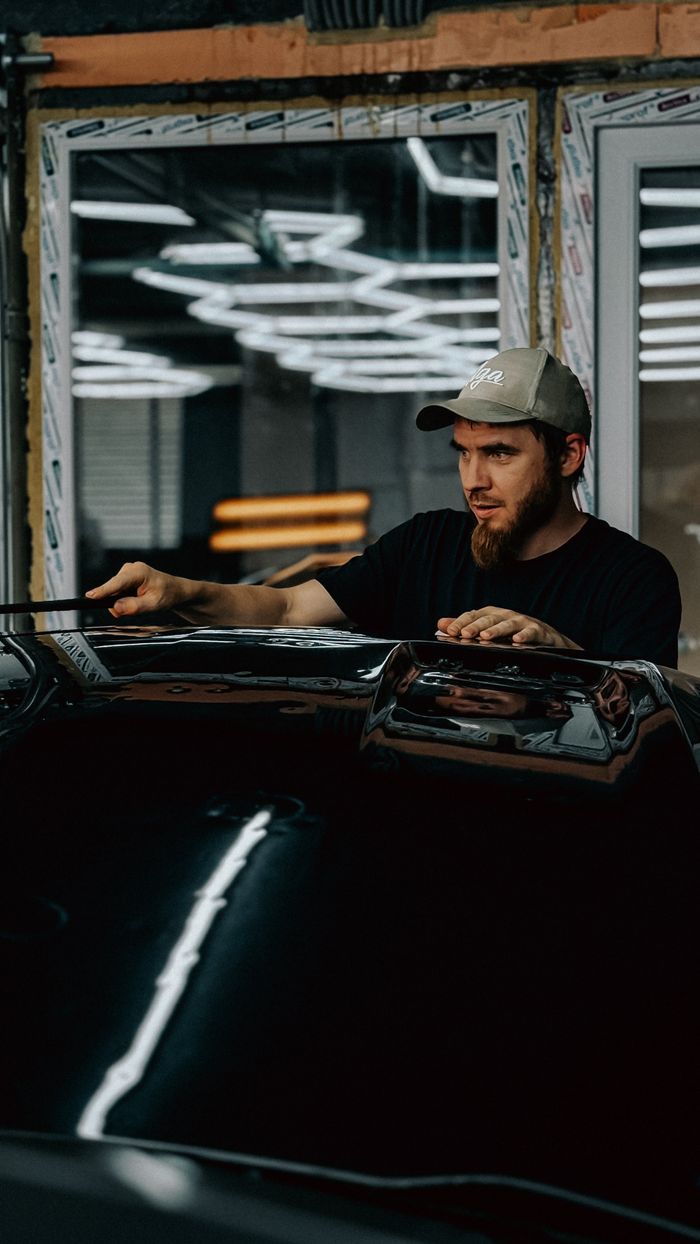 A man carefully detailing a car in a modern auto workshop.
