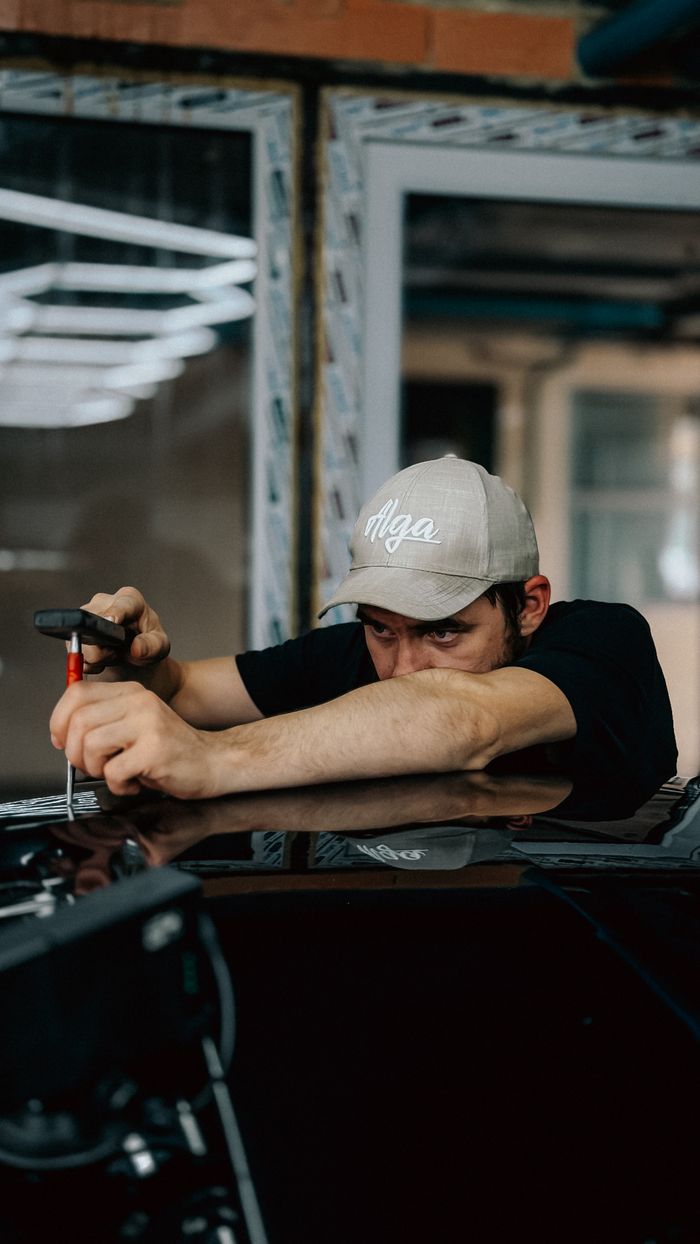 A dedicated technician repairing a car indoors, showcasing precision and skill.