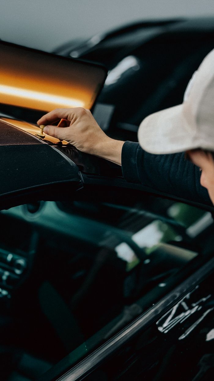 A professional detailing expert polishes a car in an automotive workshop, emphasizing quality craftsmanship.