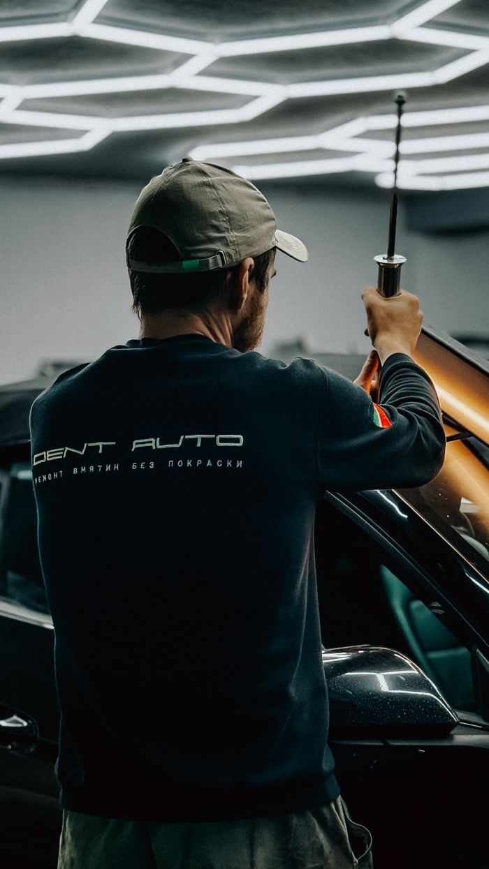 Auto technician repairing a vehicle in a modern garage setting.